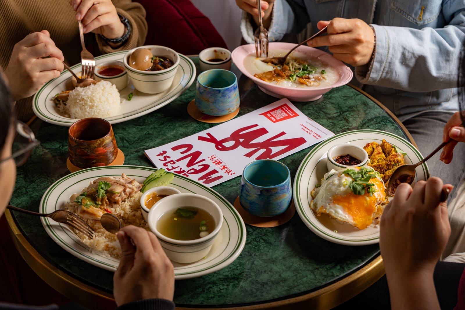 Friends sharing lunch plates around a round green marble table