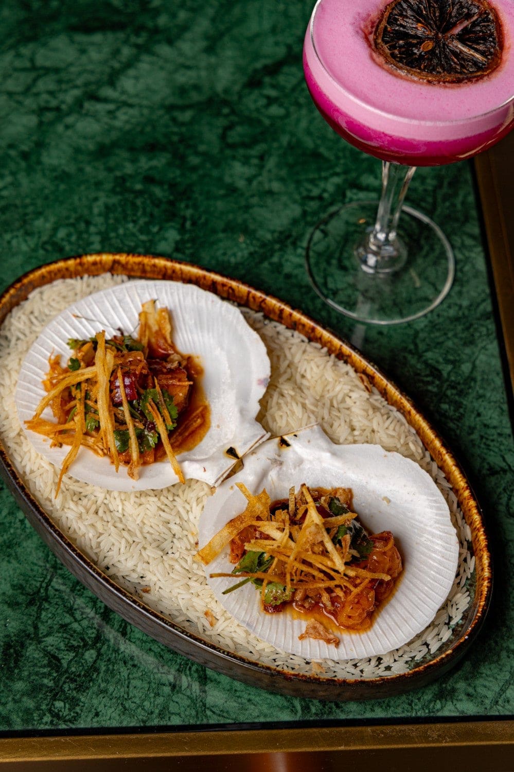 Two miang kham scallops served in shells on rice